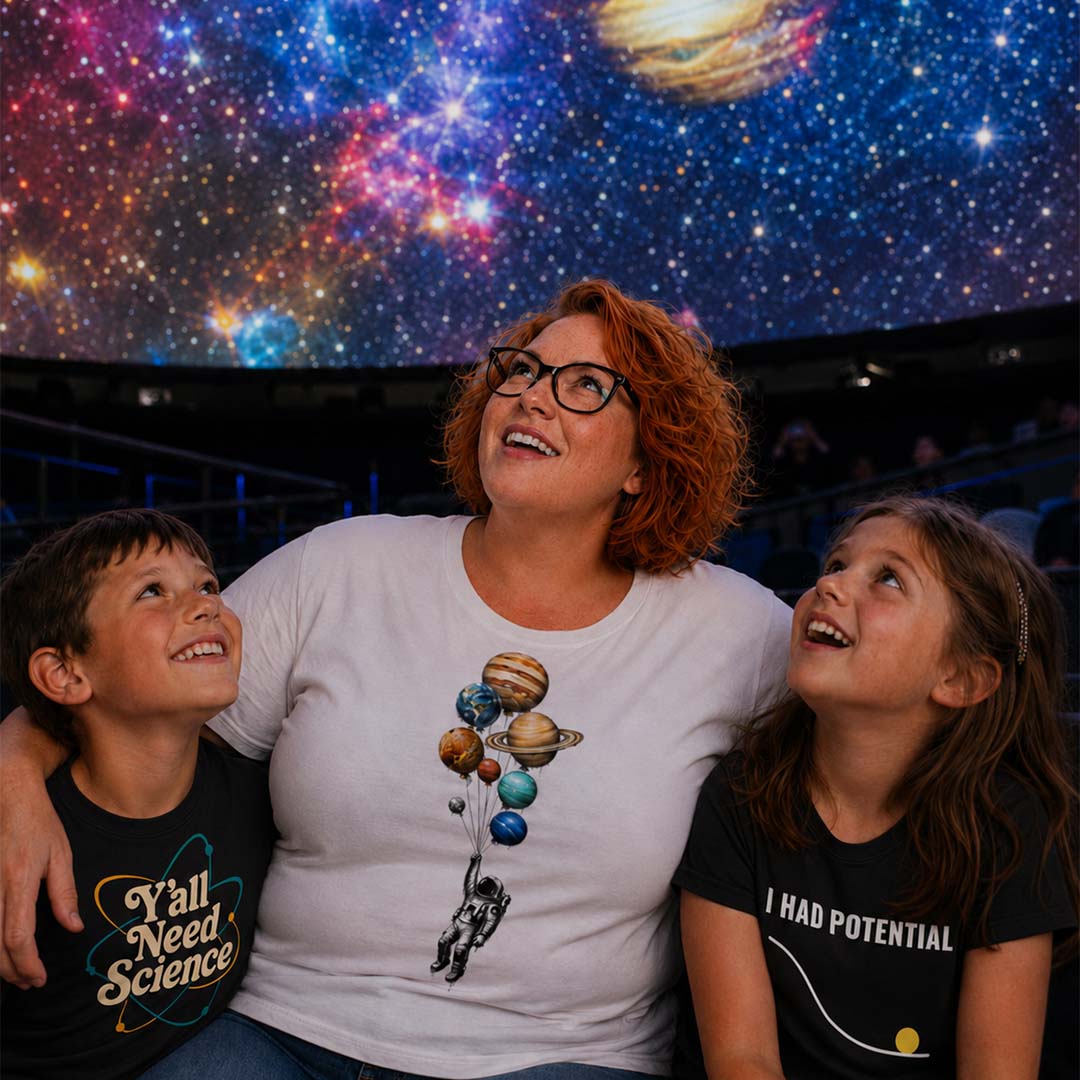 Woman with two children in a planetarium, looking up at the starry sky.