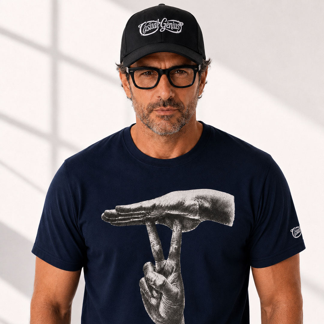 A man wearing a navy blue t-shirt with a large black and white graphic of two hands, one holding the other's wrist. He is also wearing a black baseball cap with 'Cash Genius' written on it and black-framed glasses.