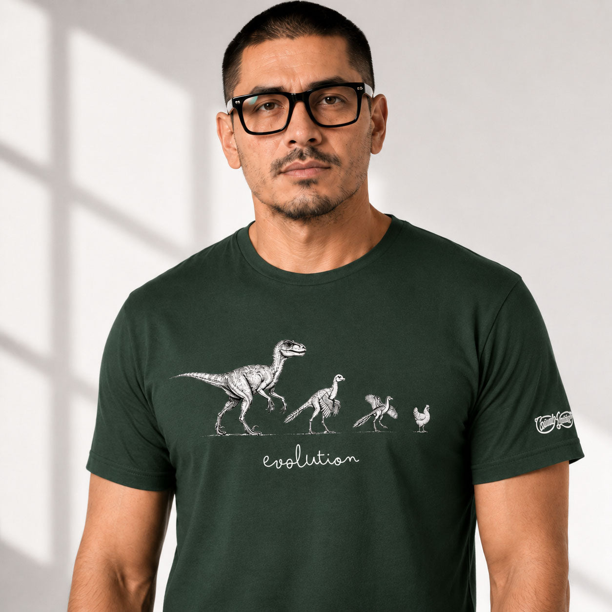 Man wearing a green t-shirt with a dinosaur evolution graphic on a light gray background