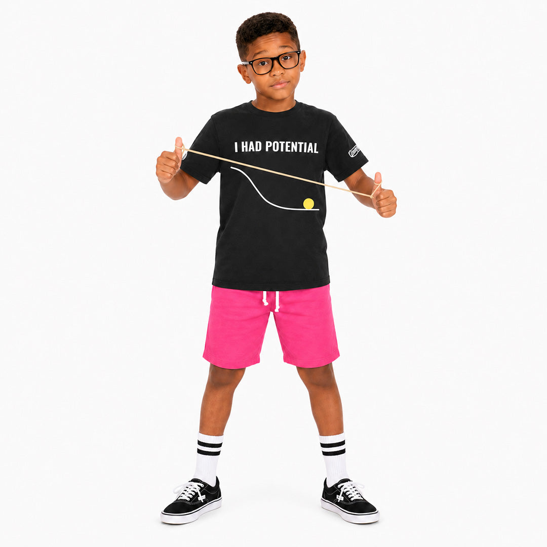 Child wearing a black t-shirt with text and pink shorts on a white background
